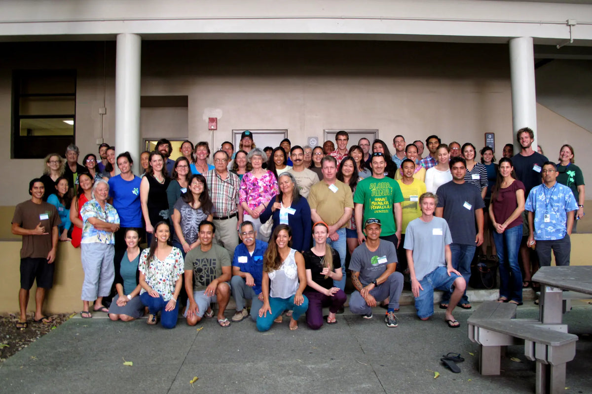 Group photo of a diverse group of people standing outdoors on a concrete surface.