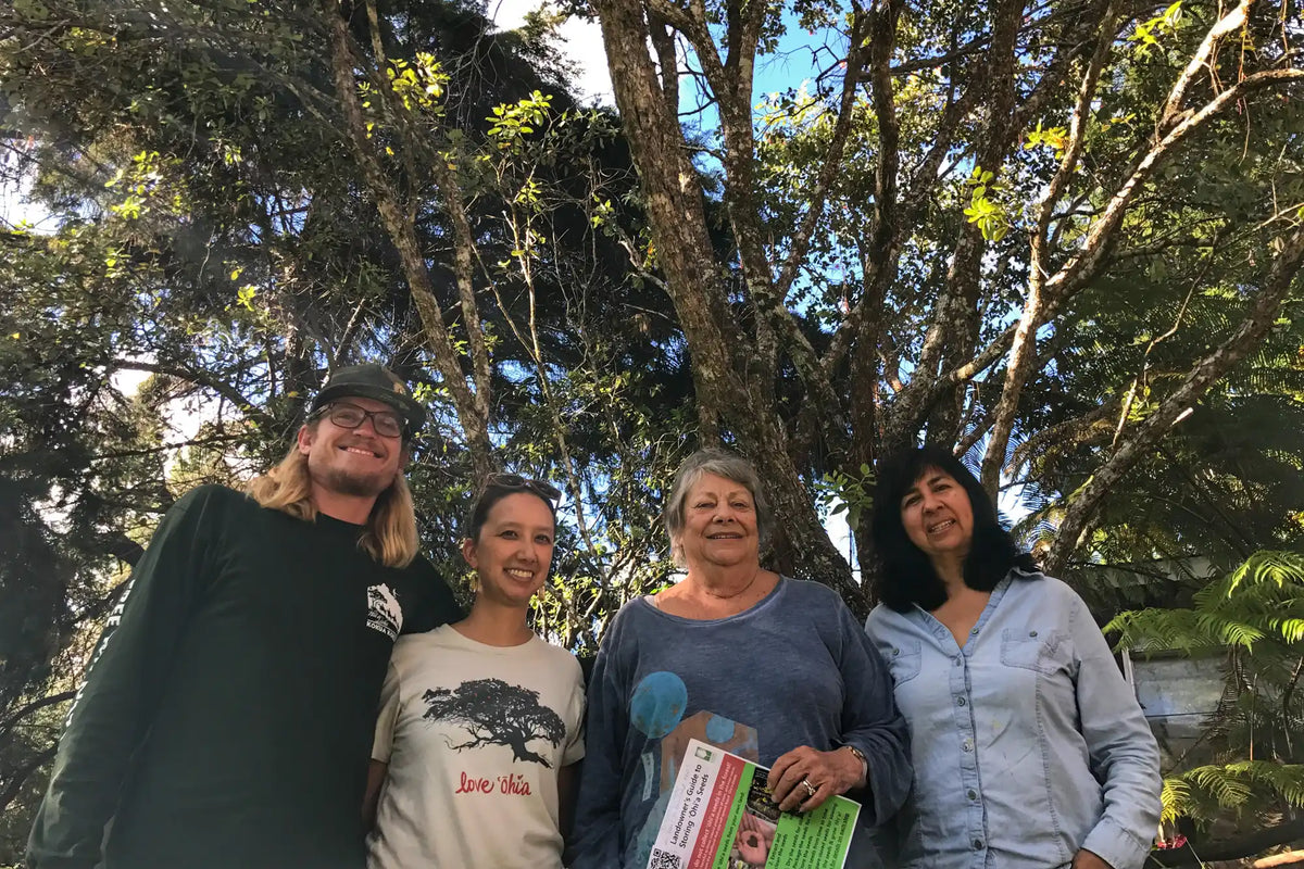 Four people standing together outdoors with trees in the background